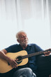 © chokniti - The old man playing guitar in the house, relax time at home