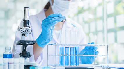 Medical or scientific researcher or man doctor looking at a test tube of clear solution in a laboratory