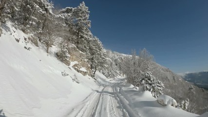 Wall Mural - Driving POV of snow covered closed mountain road.