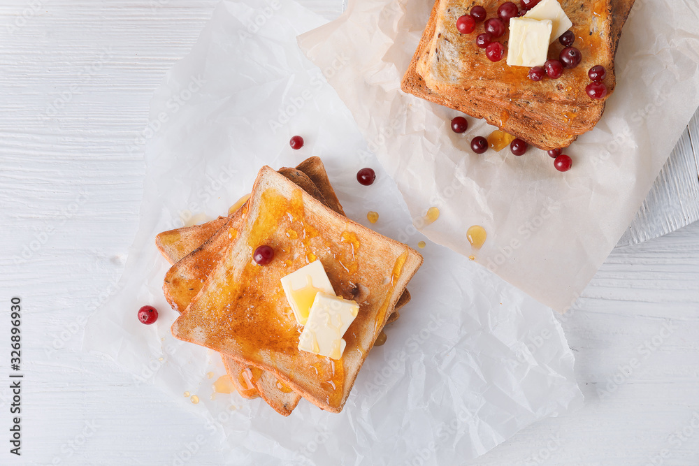 Tasty toasted bread with honey, butter and berries on table