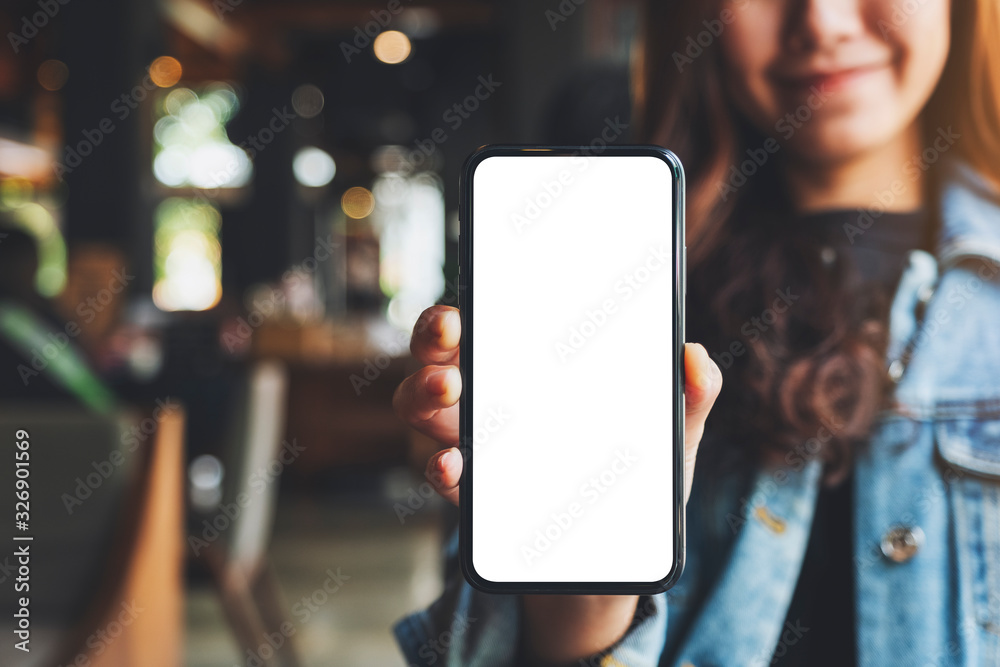 Mockup image of a woman holding and showing black mobile phone with blank white screen in cafe - obrazy, fototapety, plakaty 