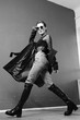 © Oleg Samoylov - Black and white fashion shot. Portrait of a fashionable girl in high boots, a long coat, jeans and sunglasses.