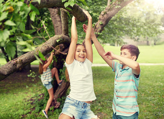 Poster - friendship, childhood, leisure and people concept - group of happy kids or friends hanging on tree and having fun in summer park