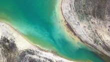 Aerial Overhead Shot Of Turquoise Water In A Lake Surrounded By Drought