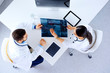 © khmelev - Medical team of doctors sitting and discussing about x-ray at table with tablets, top view