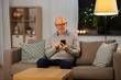© Syda Productions - technology, people and communication concept - happy smiling bald senior man texting on smartphone at home in evening