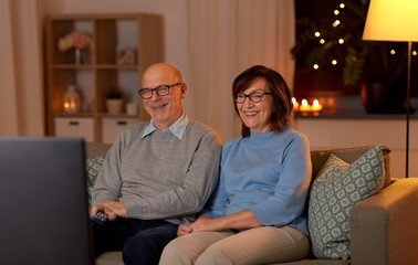 Sticker - holidays, drinks and people concept - happy smiling senior couple watching tv at home in evening