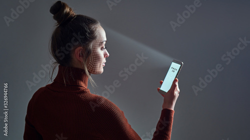 Fotografía Female scans face using facial recognition system on smartphone for biometric identification