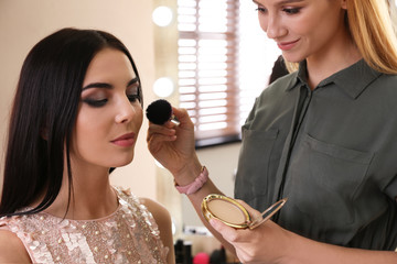 Wall Mural - Professional makeup artist working with beautiful woman in salon