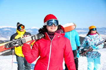 Sticker - Young woman with ski at resort. Winter vacation