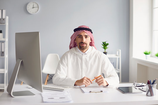 Calm arabian man sits at a table in the office. A