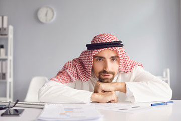 Wall Mural - Calm arab man looking sitting at a table in an office room