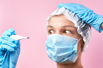 scared woman in medical mask with a thermometer