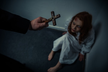 exorcist holding cross in front of obsessed girl