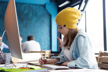 Wall Mural - Portrait of a happy casual businesswoman sitting at her workplace in office