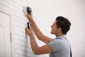 Poster - Technician installing CCTV camera on wall indoors