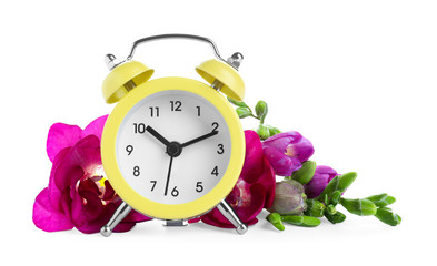 Poster - Yellow alarm clock and spring flowers on white background. Time change