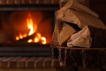 Pile Of Wood And Blurred Fireplace On Background, Space For Text. Winter Vacation