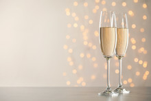 Glasses Of Champagne On Grey Table Against Blurred Lights. Space For Text