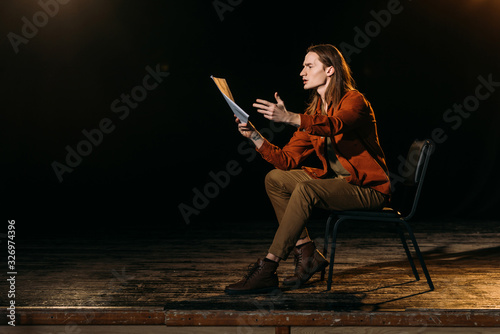 Fotomural handsome actor with scenario playing on stage during rehearse in theatre