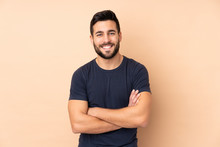 Caucasian Handsome Man Isolated On Beige Background Keeping The Arms Crossed In Frontal Position
