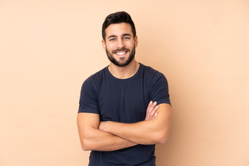 caucasian handsome man isolated on beige background keeping the arms crossed in frontal position