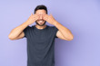 Leinwandbild Motiv Caucasian handsome man covering eyes by hands and smiling over isolated purple background