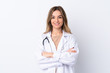 © luismolinero - Young woman over isolated white background wearing a doctor gown and with arms crossed