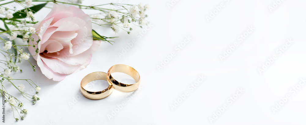 Pink flowers and two golden wedding rings on white background. - obrazy, fototapety, plakaty 