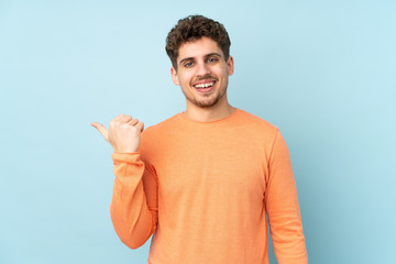 Caucasian man isolated on blue background pointing to the side to present a product