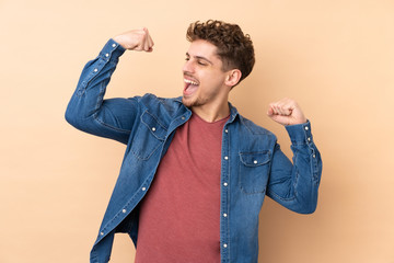 Caucasian man isolated on beige background celebrating a victory