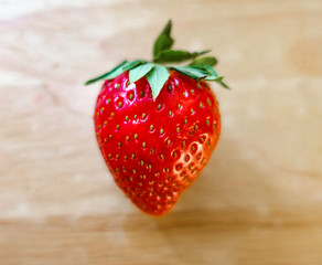 One big ripe strawberry on a wooden table