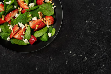 Wall Mural - Close up of bright strawberry salad with spinach on black background