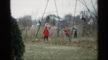 INDIANA-1959: Children Wearing Coats Playing Outside On Swing Set One Child Is Hanging Upside Down