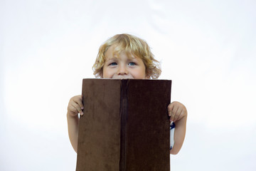 Happy little boy between 4 and 5 years old holding a book while reading it