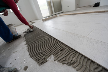 worker installing the ceramic wood effect tiles on the floor