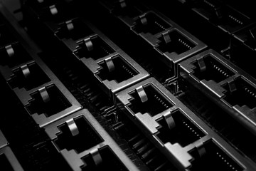 Isolated close up closely aligned multiple through hole rj45 ethernet networking hardware connectors in partial focus