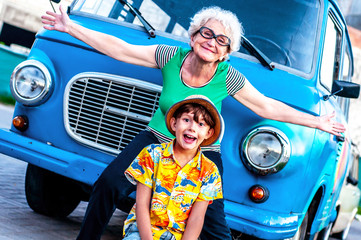 Laughing grandmother with her grandson in summer beachwear near