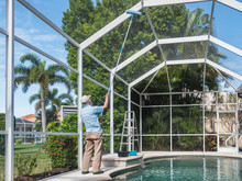 Handyman Cleaning Outdoor Pool Cage Enclosure With Pole Brush. Screened Swimming Pool Lanai Maintenance And Screen Repair.