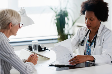 Wall Mural - A female doctor sits at her office and examining elderly female patient