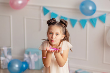 Wall Mural - Happy Birthday. Portrait of a happy cute blond girl of 7-8 years old in a festive decor with confetti.