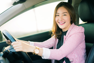 Safety driving concept, Smiling happy young  Chinese Thai Asian businesswoman driving a car in town, Confident and beautiful girl. Rear view  woman in business suit wear looking over her shoulder