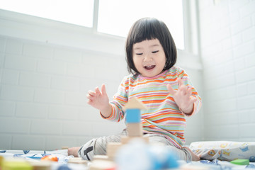 Adorable cute beautiful little Asian baby girl playing with educational wooden toys Healthy happy toddler  colorful wood block indoors at home or nursery, child learning colors  forms family concept