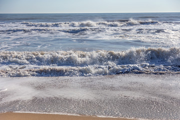 A soft sea wave rolls onto the sand of the beach. Seascape waves on the coast