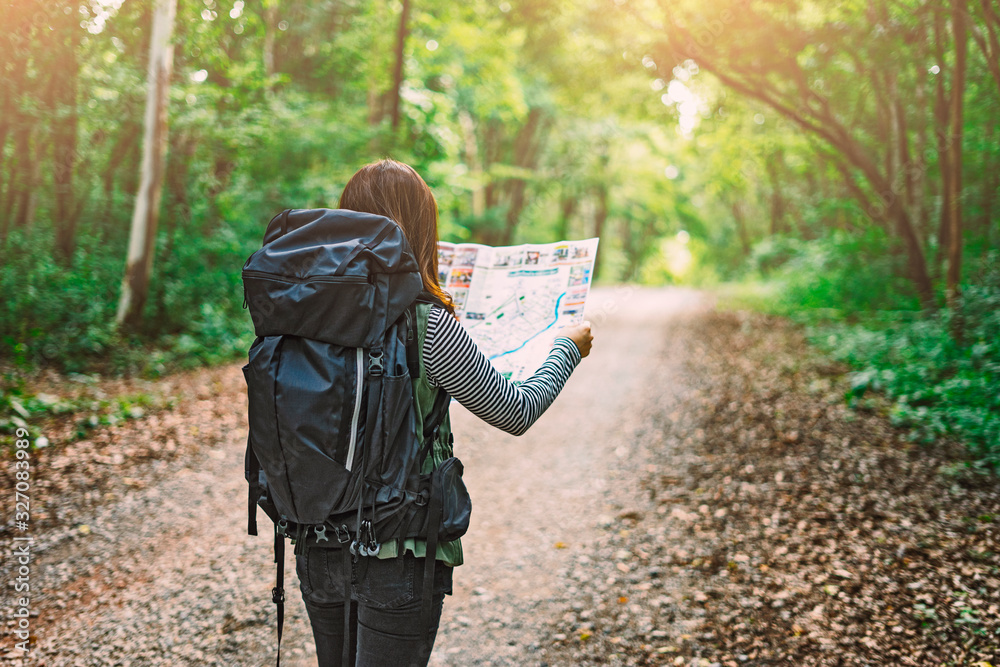 Traveling Happy Asian woman with backpack walking on path the tropical forest looking at the camera and map in green rainforests. Summer holiday and vacation trip , Survival travel, lifestyle concept - obrazy, fototapety, plakaty 