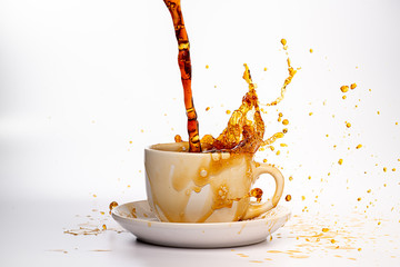  Coffee pouring into a white cup isolated against a plain white background, splashing in all directions creating a mess
