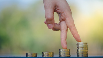 Hand with fingers business man putting on coin and looking for profit growth up,