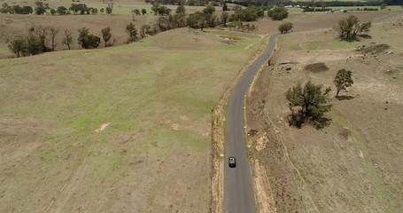 Poster - Scenic agriculture valley with cattle farms in Blue Mountains on a sunny summer day. Flying behind convertible car on a road.