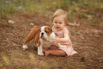 Wall Mural - Cute little baby with an English bulldog puppy, hugging. Place for the inscription. Concept: relationships, happiness, family.