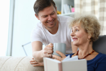 happy son brought cup tea for an elderly mother. son cares for an elderly mother at home. an adult s